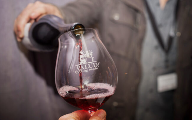 Pinot noir wine being poured into ¡Salud! logo glass