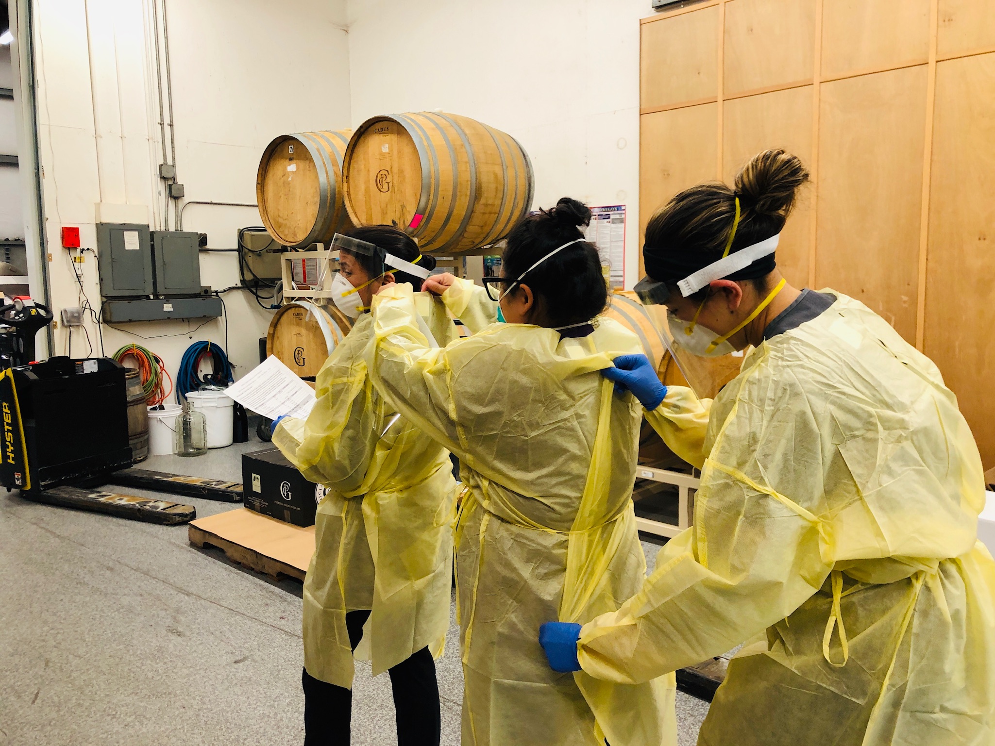 Three healthcare workers carefully put on their PPE.