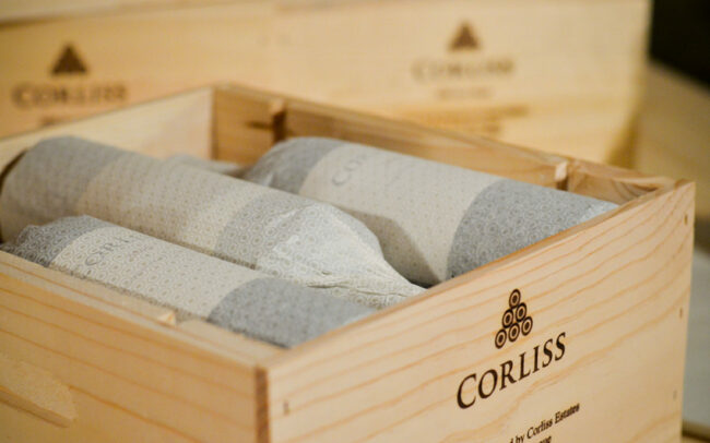 Crate of tissue paper wrapped bottles of Corliss wine