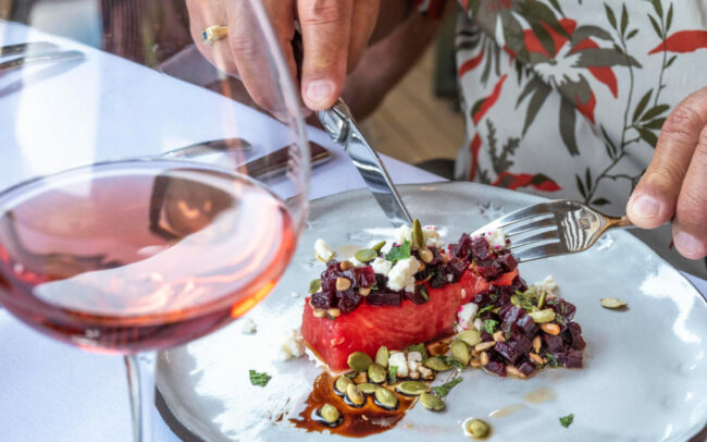 Beautifully plated salad on a white plate with a glass of Rosé